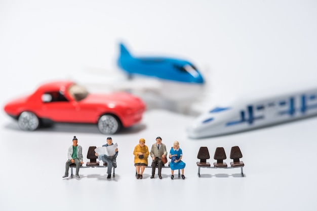 rząd figur miniaturowych siedzi na ławce z samolotu
