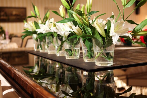 Rząd szklanek z białymi liliami na stole
