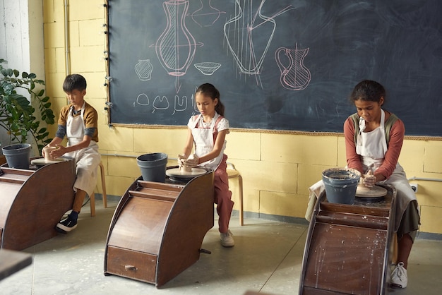 Rząd trzech międzykulturowych uczniów robiących ceramikę na lekcji