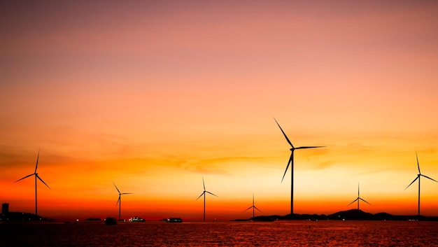 Rząd turbin wiatrowych na oceanie o zachodzie słońca