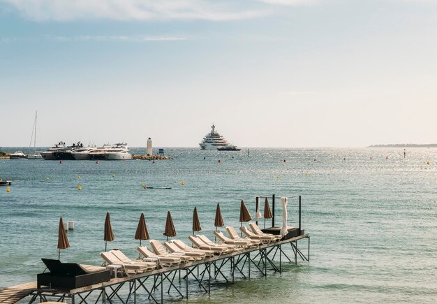 Rzędy pustych poczekalni na plaży w Juan les Pins France z super jachtami w tle