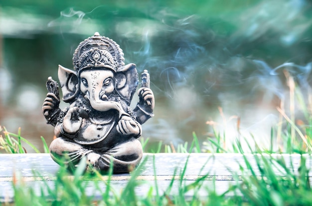 Rzeźba boga Ganesha w tle rzeki i dymu