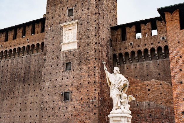 Rzeźba mężczyzny z krzyżem przy murze castello sforzesco milan italy