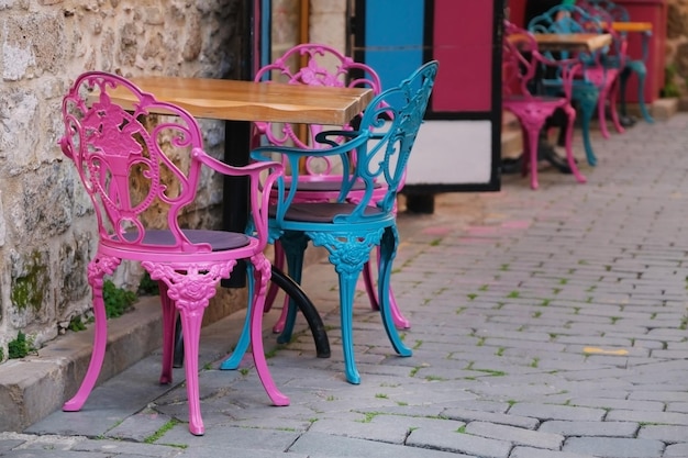 Rzeźbione kolorowe metalowe krzesła i drewniany stół w pustej ulicznej kawiarni