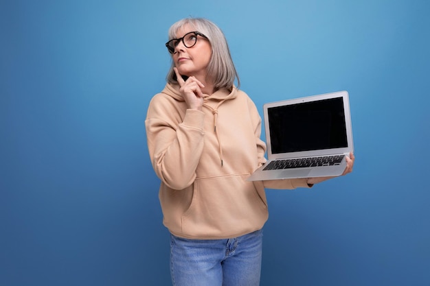 S dojrzała kobieta freelancer z siwymi włosami studiująca zdalny zawód trzymająca laptopa w rękach