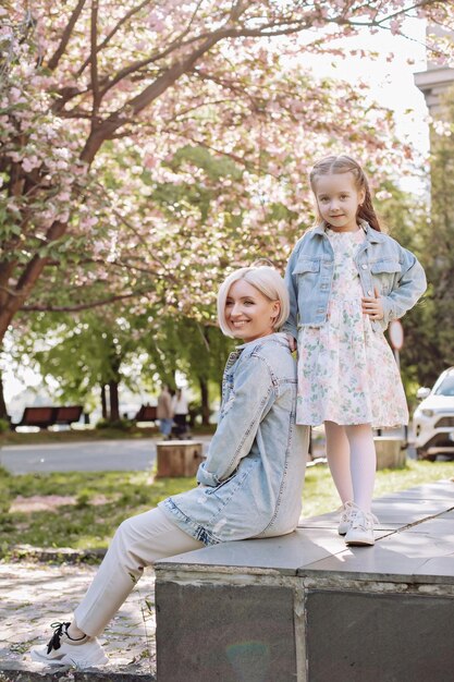 Sakura rozkwitła Młoda mama z dzieckiem bawią się w parku w pobliżu kwitnącej wiśni sakura