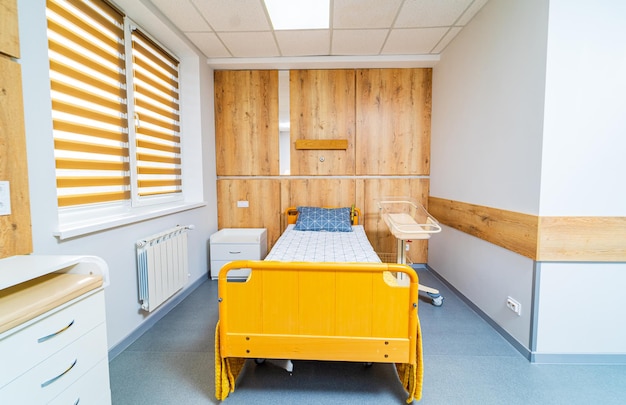 Zdjęcie sala pooperacyjna dla świeżo upieczonych matek z wygodnym łóżkiem i łóżeczkiem w pobliżu oddział szpitalny z białymi ścianami i jasnymi elementami przytulne łóżko na oddziale szpitalnym dla mam po porodzie