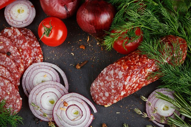 Salami pokrojone w plastry z warzywami, cebulą i pikantnymi ziołami