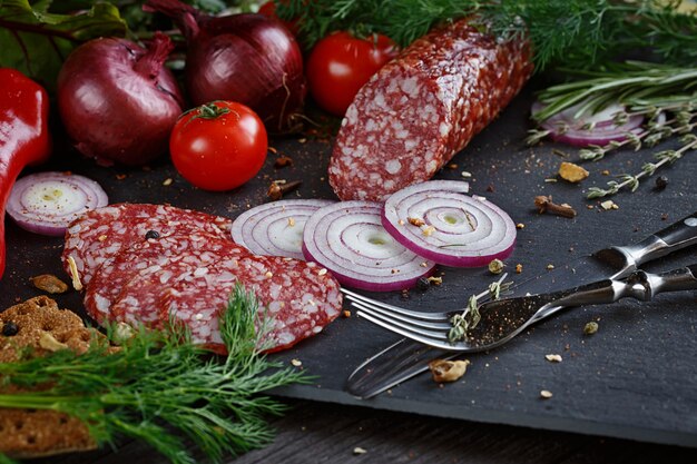 Salami pokrojone w plastry z warzywami, cebulą i pikantnymi ziołami