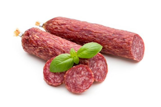 Salami wędzona kiełbasa, liście bazylii i ziarna pieprzu na białym tle.