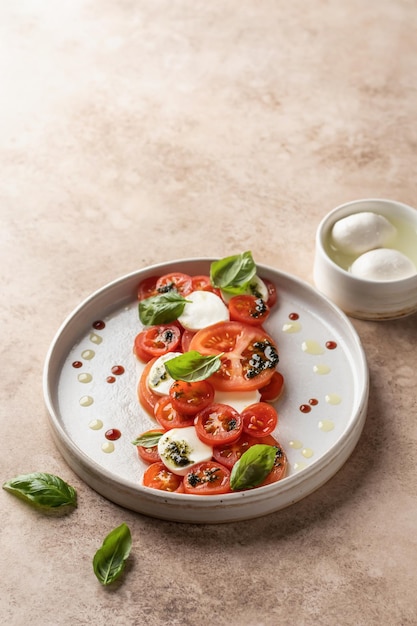 Sałatka Caprese w nowoczesnej paszy liniowej z pomidorami, bazylią, mozzarellą, pesto, sosem balsamicznym i oliwą z oliwek Tradycyjne włoskie jedzenie na beżowym tle