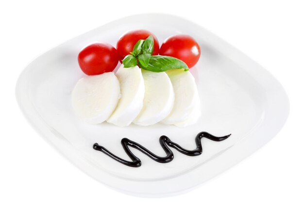 Sałatka Caprese z pomidorami z serem mozarella i bazylią na talerzu na białym tle