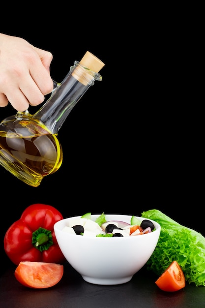 Zdjęcie sałatka jarzynowa z oliwą z oliwek wylewana z butelki.