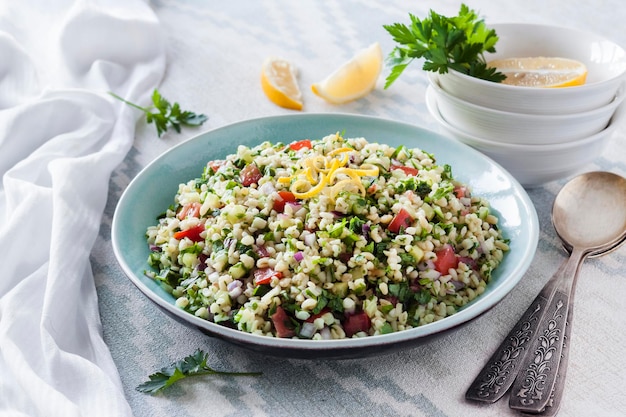 Zdjęcie sałatka tabbouleh. tradycyjna bliskowschodnia lub arabska wegetariańska sałatka z kaszą bulgur, pietruszką, miętą i pomidorem.