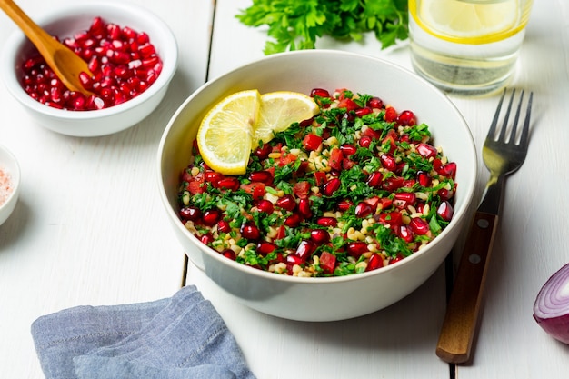 Sałatka Tabbouleh z kaszą bulgur, miętą, pietruszką, pomidorami i granatem. Zdrowe odżywianie. Jedzenie wegetariańskie.