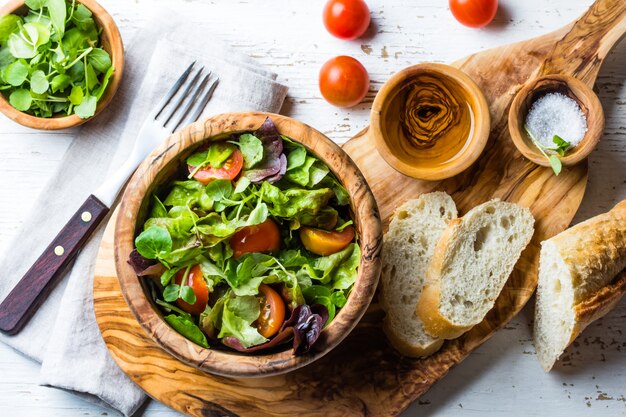 Sałatka wegetariańska z sałatą i pomidorami w drewnianej misce z oliwek