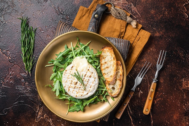 Sałatka z grillowanym serem Camembert grzanką z rukolą i rozmarynem w talerzu Ciemne tło Widok z góry