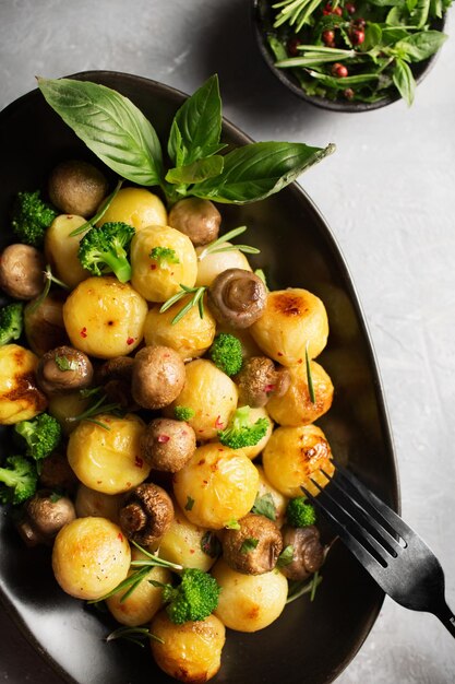 Zdjęcie sałatka z pieczonymi ziemniakami, pieczarkami brokułami i bazylią sos z pikantnego sosu ziołowego stylizacja potraw