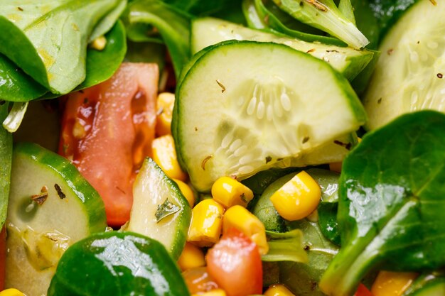 Sałatka ze szpinaku, kukurydzy, pomidorów i ogórków z oliwą. Jedzenie to prawidłowe odżywianie. Jedzenie wegetariańskie