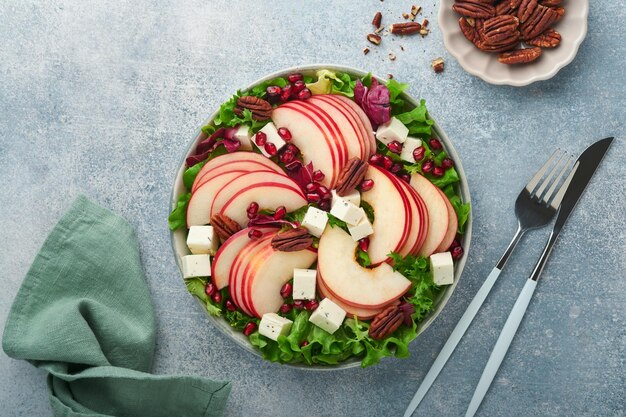 Sałatka Zielona sałatka ze świeżych owoców z serem feta, jabłkiem, granatem, pekanem i sałatą na białym talerzu Pomysł na zdrową pyszną zimową sałatkę świąteczną Zdrowe zrównoważone odżywianie Widok z góry