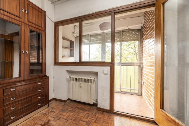 Salon domu ze starymi i brzydkimi drewnianymi meblami i dostępem do przeszklonego tarasu z drzwiami i oknami wewnętrznymi z drewnianymi ramami