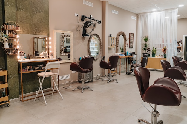 Zdjęcie salon fryzjersko-makijażowy, w którym można zobaczyć eleganckie krzesła, na których ustawiają się klienci, oraz elementy fryzjerskie