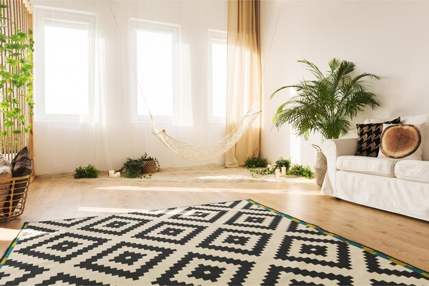 Salon z kanapą, hamakiem i dywanikiem w czarno-biały wzór.
