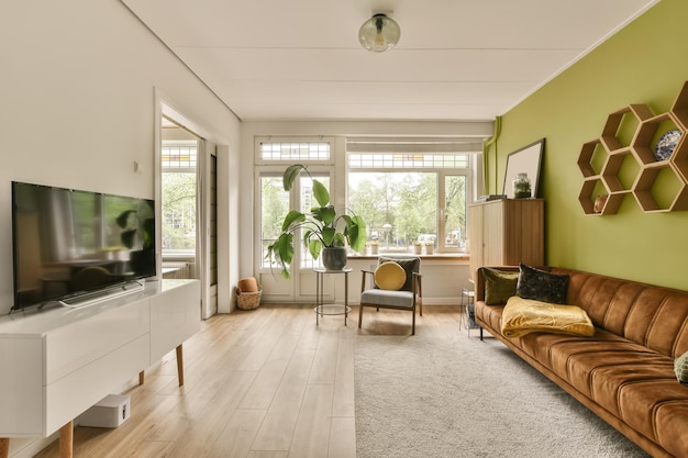 Salon z zielonymi ścianami i białymi wykończeniami na ścianach. Na środku pokoju znajduje się pomarańczowa kanapa