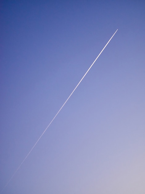 Sam samolot w błękitne fioletowe niebo ślad białą linię ukośną