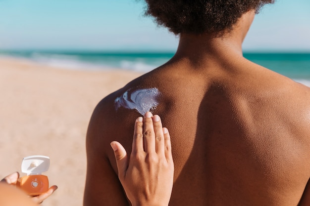 Zdjęcie samica stosowania sunblock na plecach czarny mężczyzna