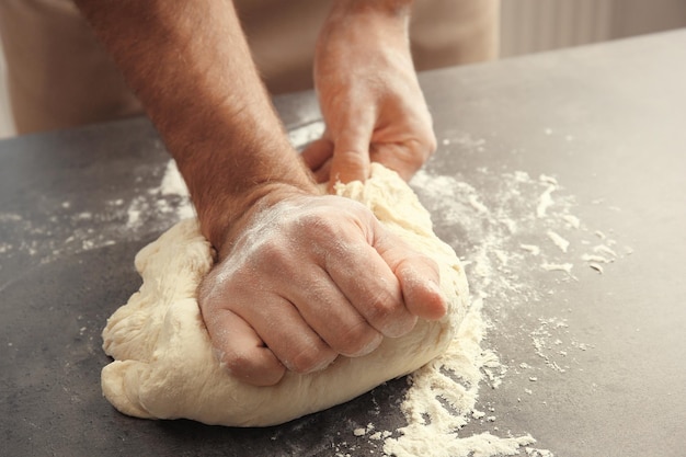 Samiec wręcza przygotowywać ciasto dla pizzy na stołowym zbliżeniu