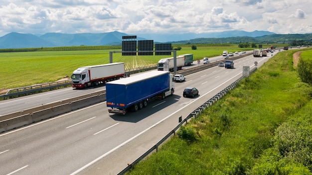 Samochód i ciężarówki pędzące na autostradzie wielopasmowej na obwodnicy Turynu, Włochy.