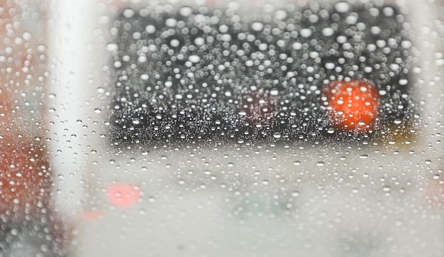 Samochód jedzie w deszczu z zamazanym samochodem w tle.