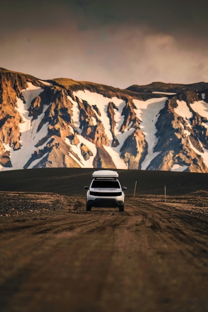 Samochód SUV 4x4 jadący po polnej drodze i wulkanicznym tle górskim na islandzkich wyżynach latem w Landmannalaugar