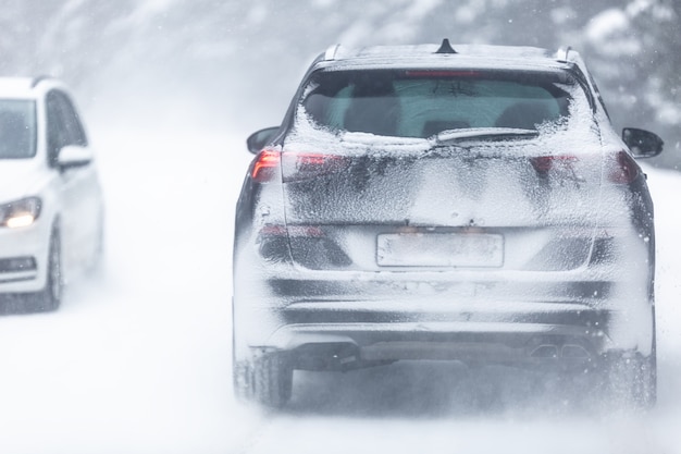 Samochód Typu Suv Jadący Po Zaśnieżonej, śliskiej Drodze W Lesie, Posiadający Numer Rejestracyjny Niewidoczny Ze Względu Na śnieg.