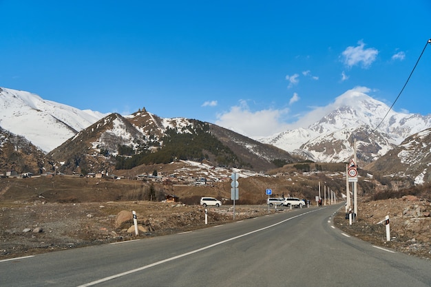 Samochodowa górska droga prowadząca do podnóża góry Kazbegi. Czapka śnieżna na szczycie góry