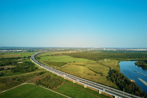 Samochody jadące autostradą w pobliżu zielonych pól widok z góry z lotu ptaka dron widok asfaltowej drogi z ruchem samochodowym