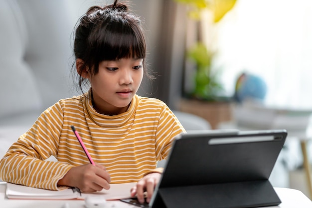 Samodzielna izolacja dziecka używającego tabletu do odrabiania zadań domowychDziecko robiące przy użyciu cyfrowego tabletu wyszukującego informacje w Internecie podczas covid 19 lock downDomowe nauczanieOdległość społecznaEdukacja online