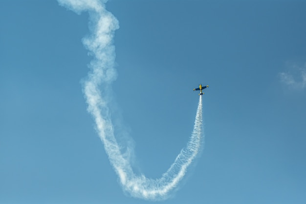 Samolot akrobacyjny ze śladem dymu na niebie
