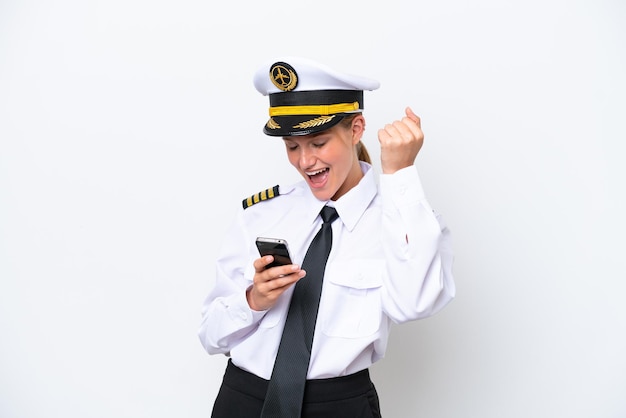 Samolot kaukaski pilot kobieta na białym tle z telefonem w pozycji zwycięstwa