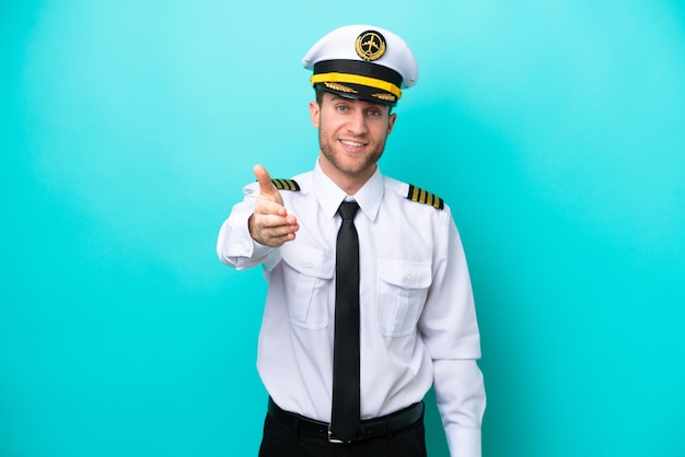 Samolot kaukaski pilot na białym tle na niebieskim tle, ściskając ręce, aby zamknąć dobrą ofertę