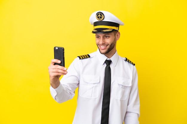 Samolot kaukaski pilot na białym tle na żółtym tle robi selfie