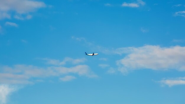 Samolot na tle błękitnego nieba z chmurami.