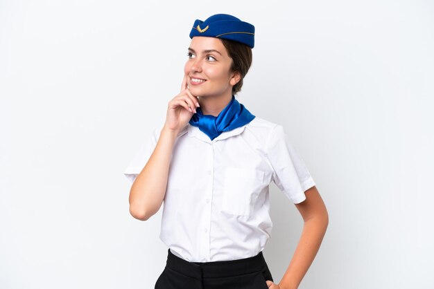 Samolot stewardessa kaukaska kobieta na białym tle myśląca o pomyśle, patrząc w górę