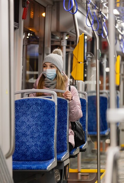 Samotna dziewczyna w masce na twarzy jeździ nocą tramwajem w czasie pandemii