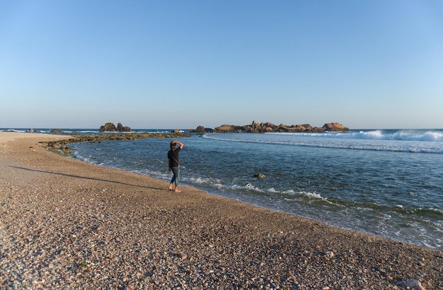 Samotna kobieta spacerująca, ciesząca się pięknem plaży