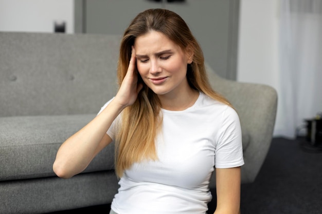 Samotna kobieta z bólem głowy lub migreną, mdłościami, siedząca w domu. Koncepcja depresji