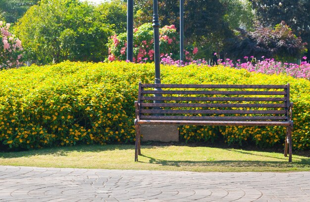 Samotna metalowa ławka dekoracyjna w ogrodzie kwiatowym