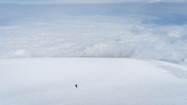 Zdjęcie samotny alpinista idący po wielkim lodowcu nad chmurami na górze ararat w turcji