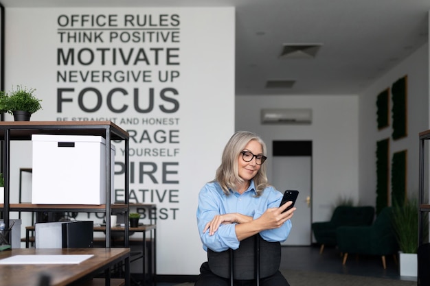 Samowystarczalna i pewna siebie bizneswoman trzymająca telefon w dłoniach w biurze